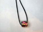 Cz pendant outsourcing agent wholesales fashion accessories. Small Cylindrical silver plated pendant with multicolored cz gems inlaid throughout and hanging from black cord necklace