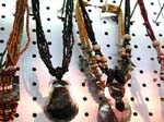 China export agent supplies bead and shell jewelry necklace. Dark colored, oval shaped stone pendant hanging on beaded and shell necklace