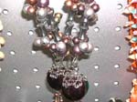 Bead and shell necklace wholesaler supplies jewelry to retail stores. Large beaded necklace with silver cylinders holds large colored globe by lacey silver design
