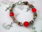 Silver charm bracelet supplied by China wholesale distributor. Silver charm bracelet with rock styled beads, red gemstone beads, and silver cross charms dangling with toggle clasp for closure.