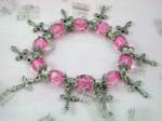Gemstone charm bracelet supplied at wholesale price from China international importer. Pink color beads with silver cross charms and flowery beads on strecthy charm bracelet