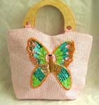 Womens designer handbags distributed from China importing wholesaler. Pink canvas fabric with sequins wooden handle handbag motif butterfly feature in sparkle chips and thread work design with zipper closure and inner zipper pocket
