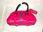 China sourcing agent supplies lady hand bag products. Pink imitation leather purse with black buckles, double handles, and buttons along with a black and silver designed strip in center.