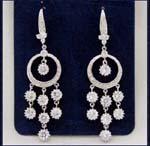 Boutique collection wholesale comapny distributes cz jewelry fashions. Three rows of cz stones hanging below rhodium plated hoop with another cz stone in center held by elongated studs
