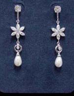 Quality earrings made with cz gemstones supplied wholesale online. Tear drop imitation pearl with cut out circle above is suspended by rhodium plated pole with flower in center and cz stone in stud