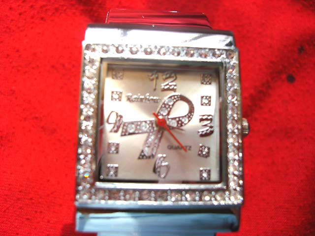 Accessory gift exporter - Cancer ribbon symbol in clock face of silver watch with stones around frame 