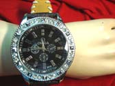 Large omega style gemstone inlaid frame on yellow thin strap with white stitching 