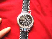 Black strap with white stitching holding classic kinetic style watch clock