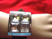 Three large gemstones on girls fashion watch with clock in bottom corner