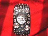 Black bangle bracelet watch with a variety of sized cz gems on strap