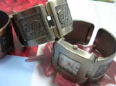 Capital lettering motif on wide bangle bracelet watch with squared clock face
